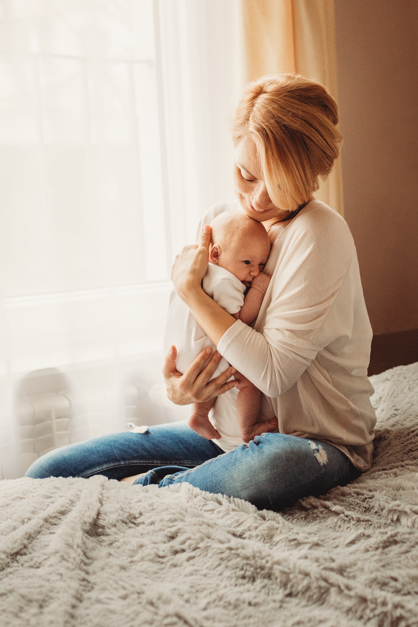 mama przytula noworodka siedząc la łóżku