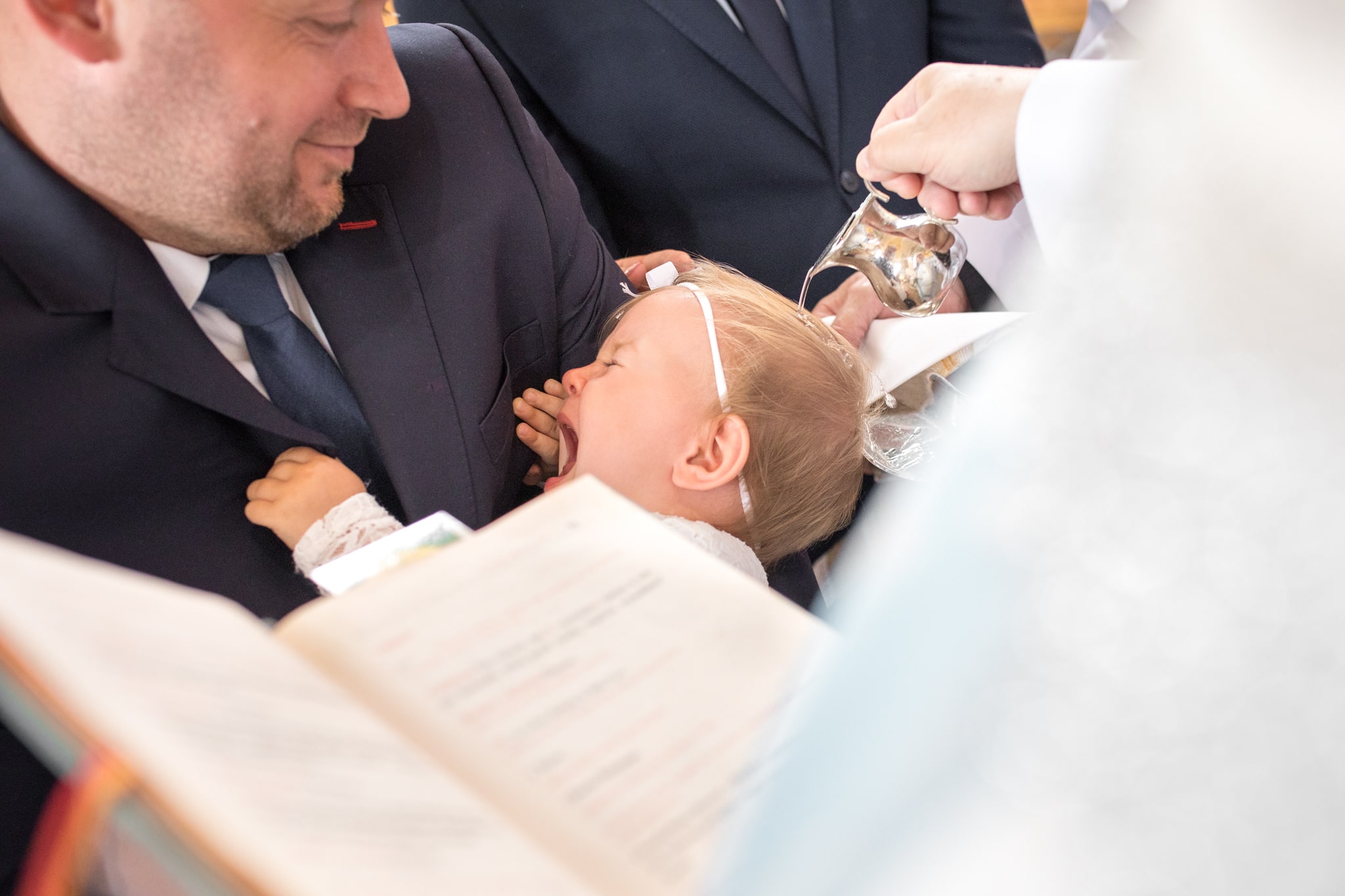 ksiądz polewa głowę dziecka podczas chrztu 