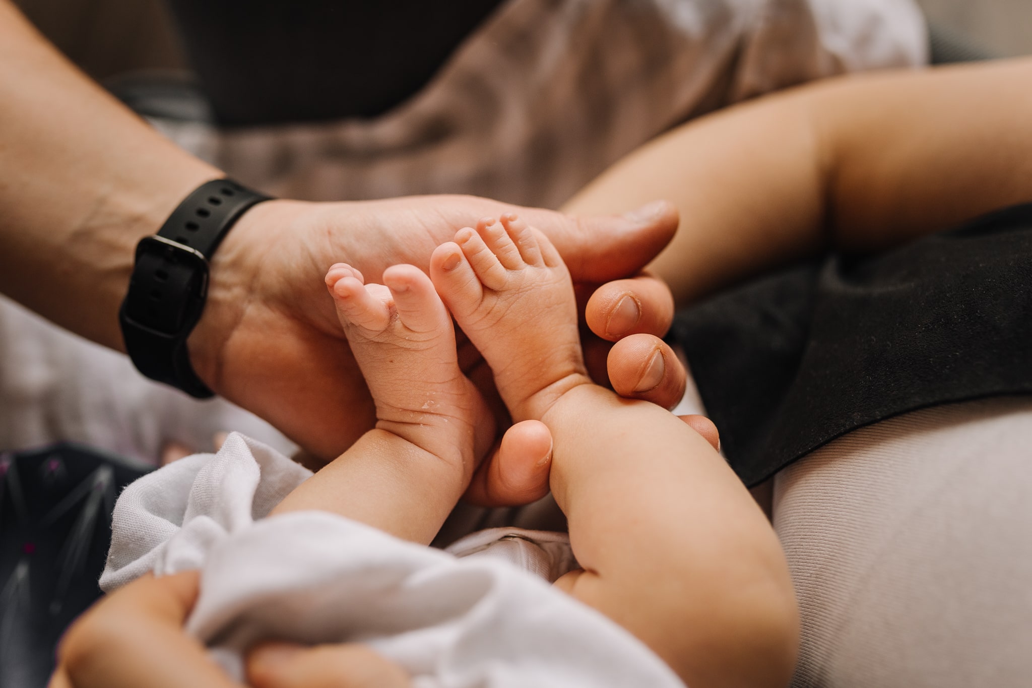 maleńkie stópki noworodka trzymane przez męskie dłonie
